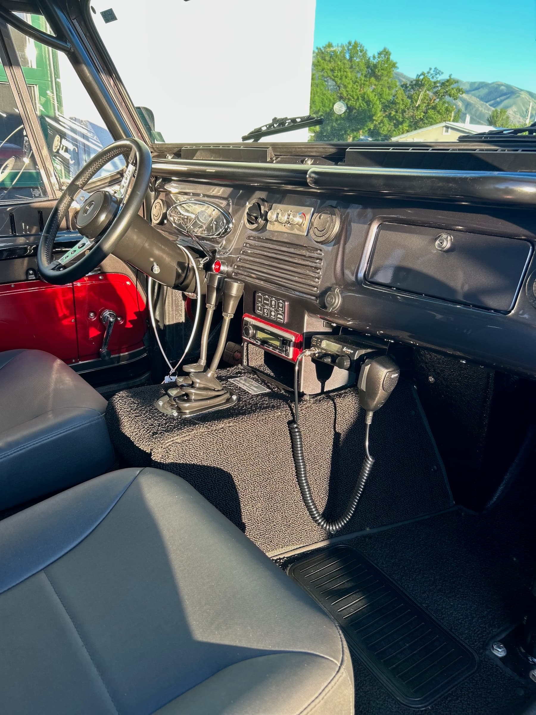 Restored vintage vehicle interior featuring a black dashboard, dual gear shifters, and CB radio.